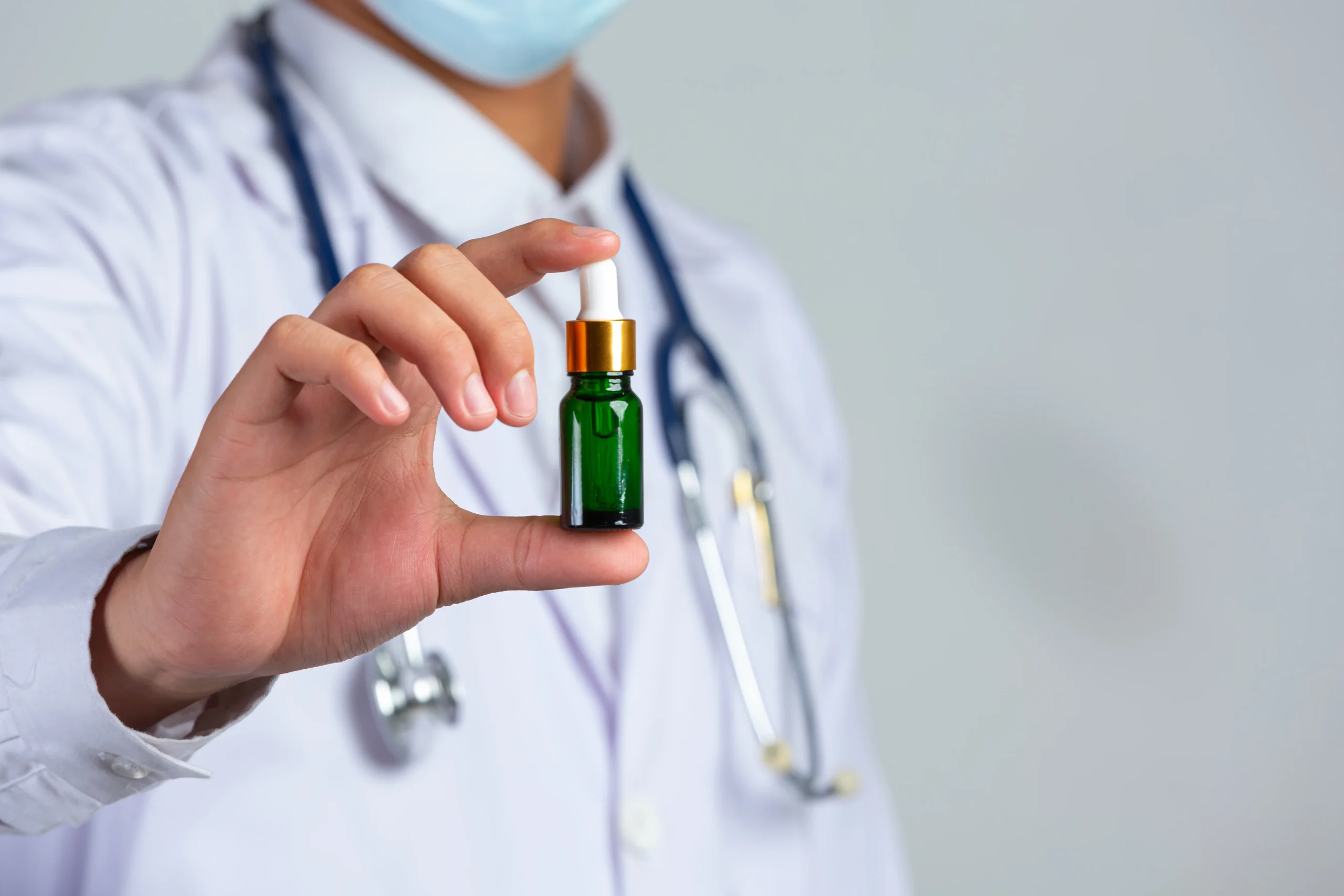 close-up-picture-of-medical-doctor-holding-bottle-of-cannabis-oil-on-white-wall